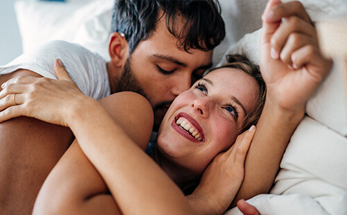 Ein Pärchen liegt Arm in Arm im Bett.