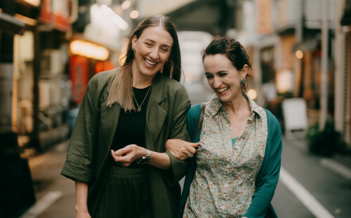 Zwei Frauen gehen lachend nebeneinander.