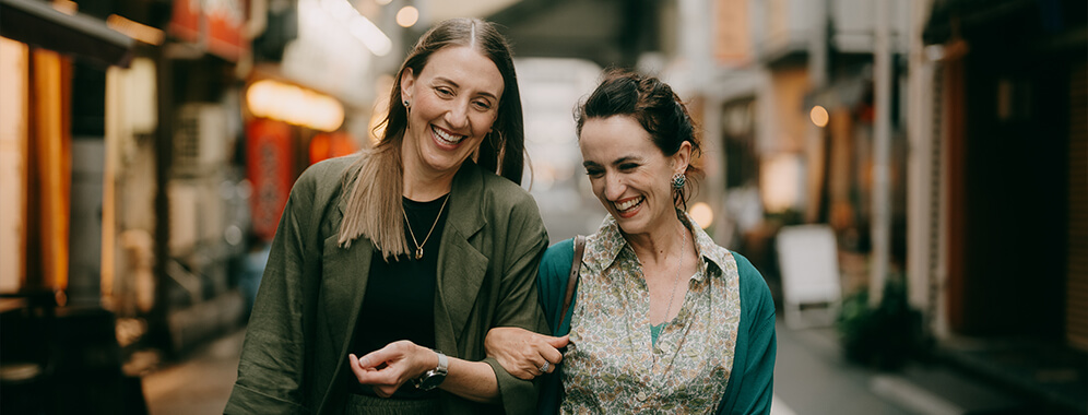 Zwei Frauen gehen lachend nebeneinander.