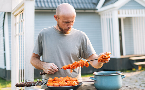 Ein Mann steckt Fleischstücke auf einen Grillspieß.