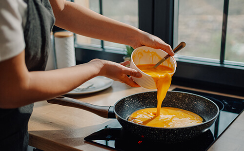 Eine gelbliche Flüssigkeit wird in eine Pfanne gekippt.