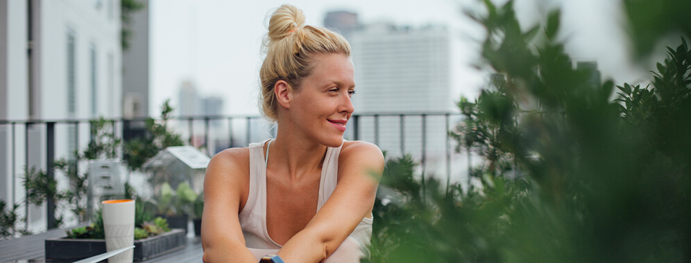 Eine Frau sitzt auf dem Balkon und schaut in die Ferne. 