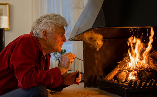 Ein Mann raucht am Kamin.