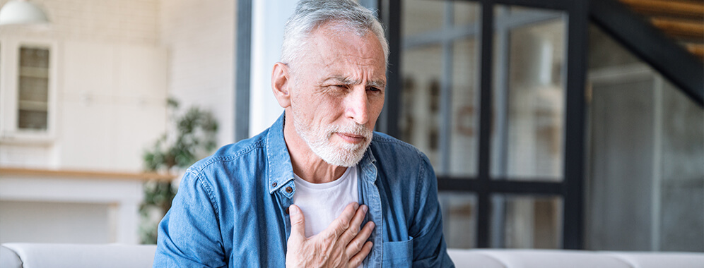 Ein Mann hält sich die Brust.