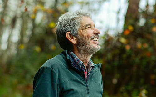 Ein Mann ist draußen und lächelt.