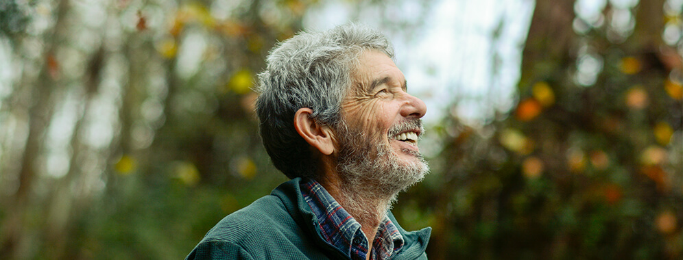 Ein Mann ist draußen und lächelt.