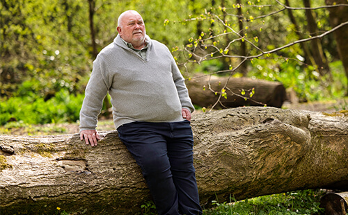 Man sieht einen übergewichtigen Mann im Wald