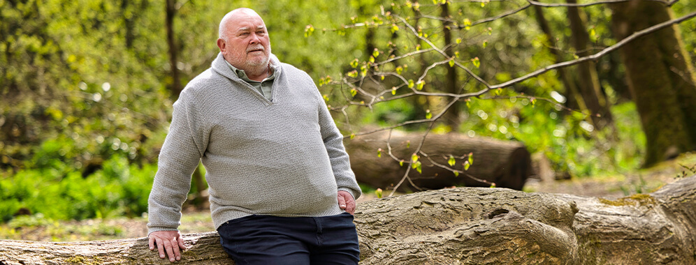 Man sieht einen übergewichtigen Mann im Wald.