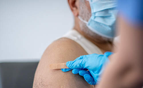 Nach einer Impfung wird ein Pflaster auf den Oberarm geklebt.