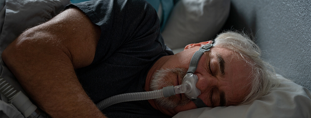Ein Mann schläft mit einer Atemmaske.