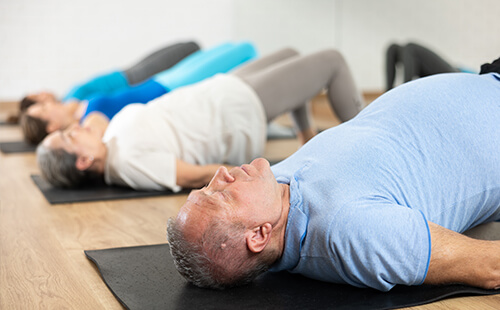 Ein Mann liegt auf dem Rücken auf einer Yogamatte und macht eine Übung.