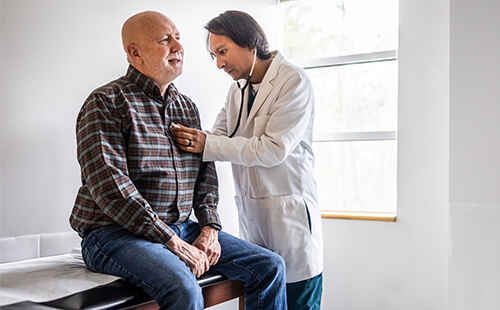 Ein Mann wird beim Arzt abgehört.