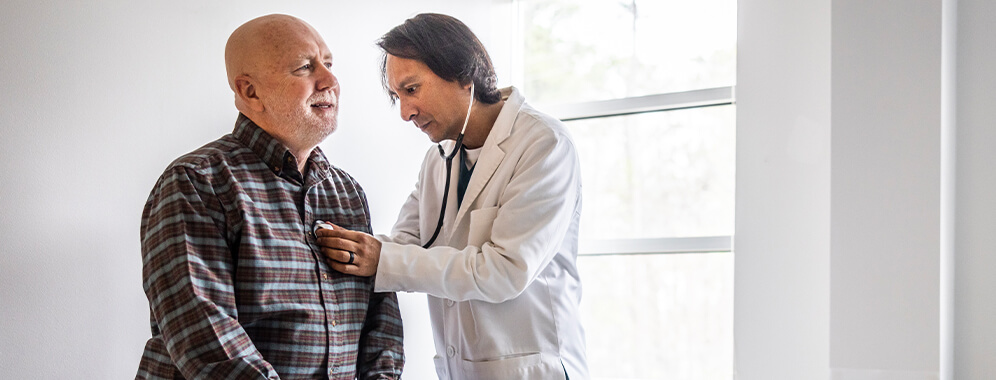 Ein Mann wird beim Arzt abgehört.