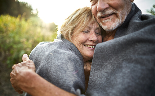 Eine Frau wird von ihrem Mann umarmt.