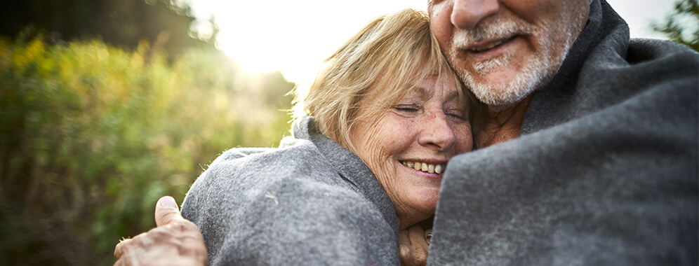 Eine Frau wird von ihrem Mann umarmt.