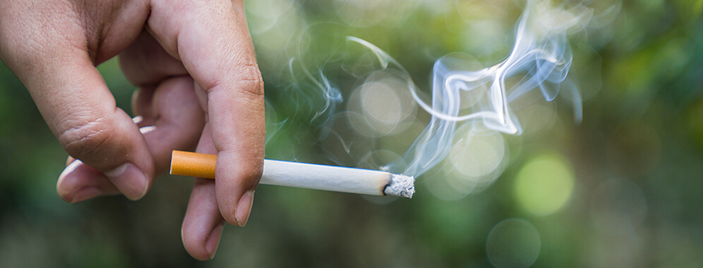 Eine Hand hält eine qualmende Zigarette