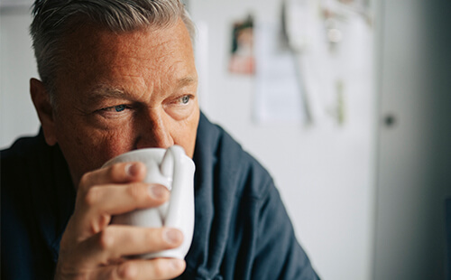 Ein Mann trinkt aus einer Tasse.
