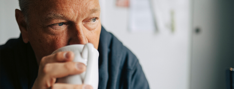 Ein Mann trinkt aus einer Tasse.