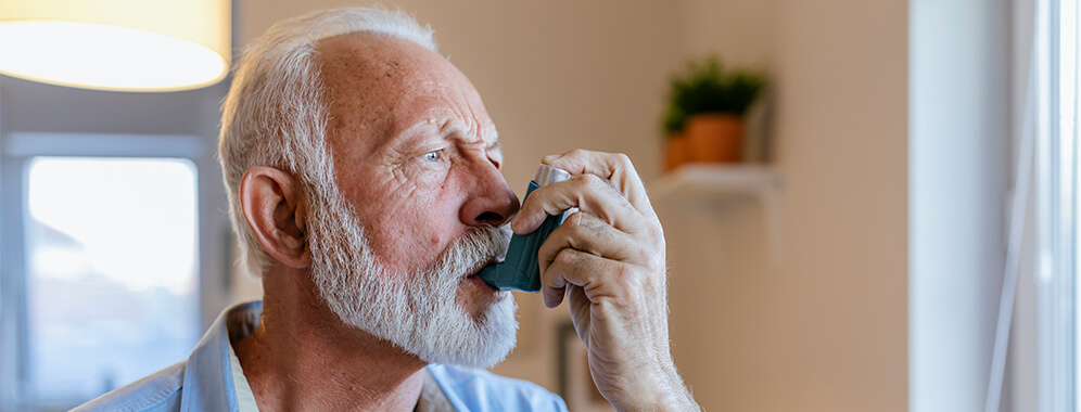 Ein älterer Mann benutzt einen Inhalator.