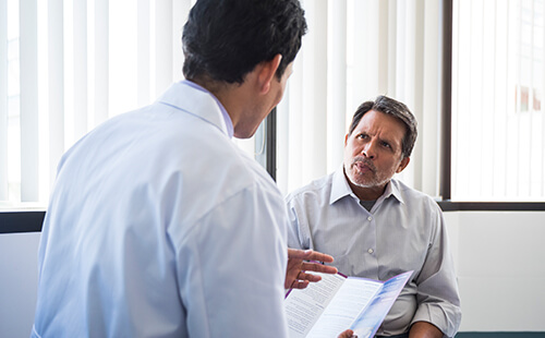 Ein Mann bei Dehnübungen auf dem Boden sitzend. 