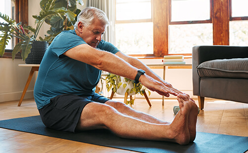 Ein Mann bei Dehnübungen auf dem Boden sitzend. 