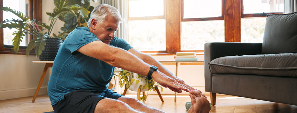 Ein Mann bei Dehnübungen auf dem Boden sitzend. 