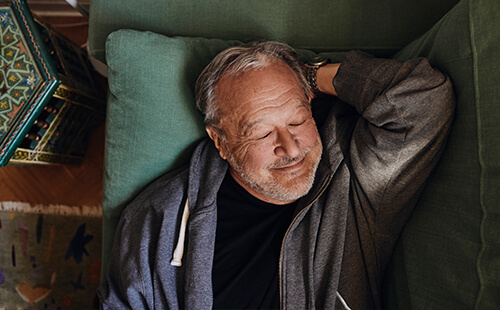 Ein Mann liegt schlafend auf der Couch. 