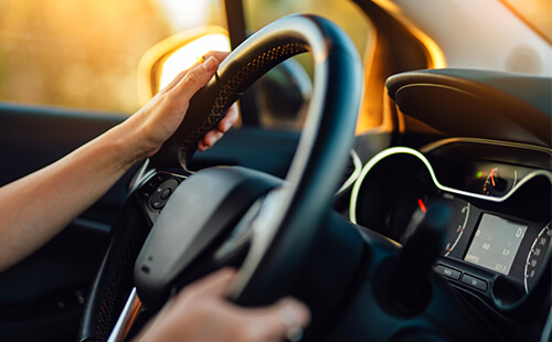 Hand hält Lenkrad im Auto.