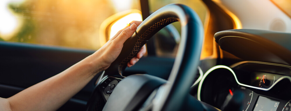 Eine Hand hält ein Lenkrad im Auto.