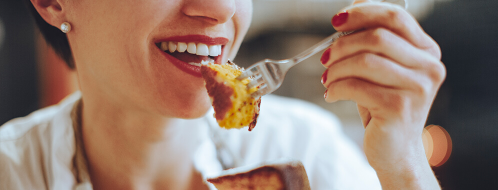 Eine Frau isst ein Stück Kuchen, der mit Zuckerersatz gebacken wurde.