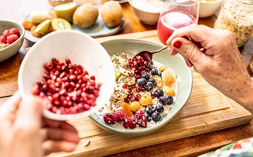 Man sieht ein gesundes Müsli mit viel Obst, Haferkleie und Joghurt.