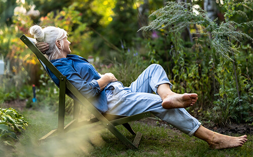 Eine Frau (Diabetikerin) liegt im Sommer im Garten auf einem Liegestuhl. 
