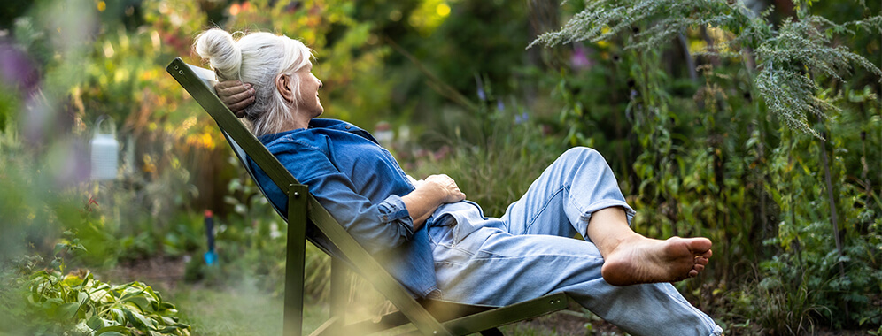 Eine Frau (Diabetikerin) liegt im Sommer im Garten auf einem Liegestuhl.