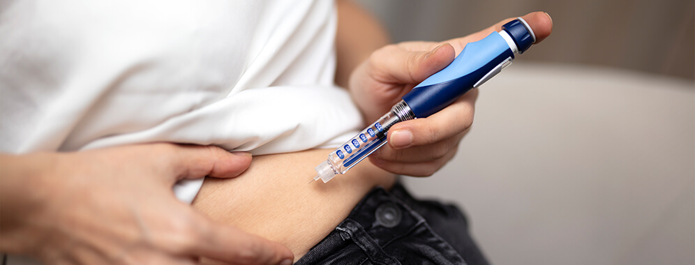 Eine Person injiziert sich eine Pen in den Bauch. 