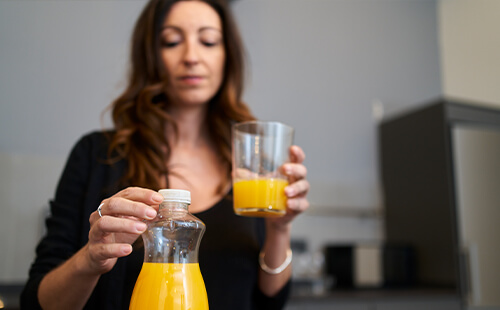 Eine Frau hält ein Glas mit Orangensaft in der Hand. 