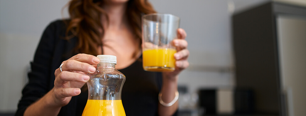 Eine Frau hält ein Glas mit Orangensaft in der Hand.