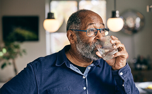 Ein Mann mit Diabetes trinkt ein Glas Wasser.
