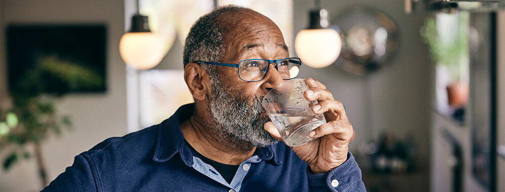 Ein Mann mit Diabetes trinkt ein Glas Wasser.