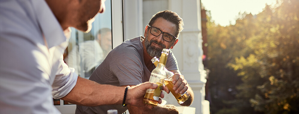 Zwei Männer stoßen mit Bierflaschen an.