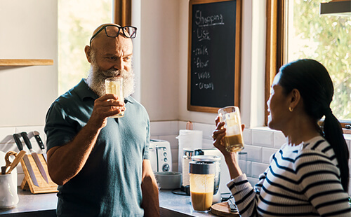 Ein Mann und eine Frau trinken in der Küche einen Shake. 