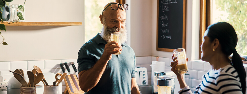 Ein Mann und eine Frau trinken in der Küche einen Shake.