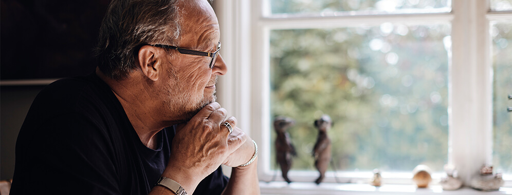 Ein älterer Herr mit Diabetes schaut aus dem Fenster.