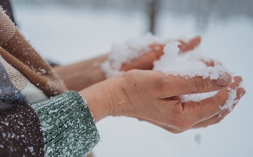 Hände halten Schnee.