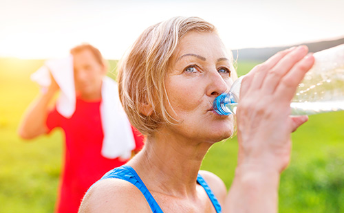 Eine Frau trinkt nach dem Sport aus einer Wasserflasche