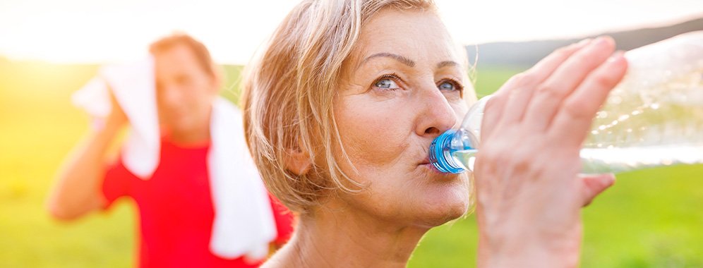 Eine Frau trinkt nach dem Sport aus einer Wasserflasche. 