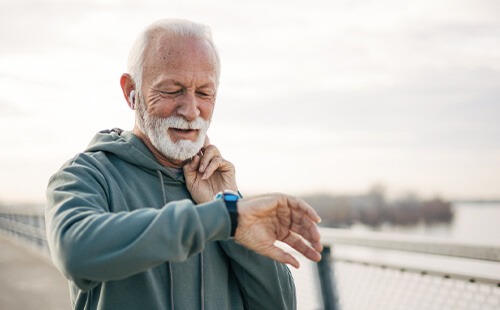 Ein älterer Herr ist gejoggt und misst sich den Puls.