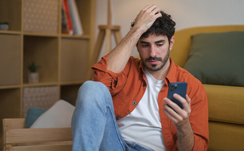 Ein Mann liest nachdenklich etwas auf dem Handy.