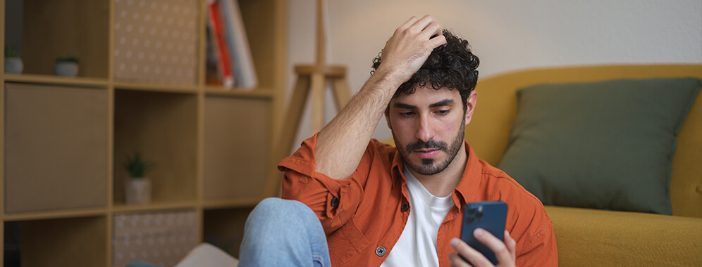 Ein Mann liest nachdenklich etwas auf seinem Handy.