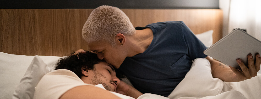 Ein Mann gibt seinem Partner einen Kuss auf die Stirn. 