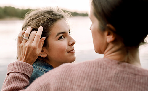 Eine Frau streicht ihrer Tochter übers Gesicht.